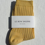 Mustard yellow sock with 'Le Bon Shoppe' label on a light gray background