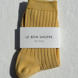 Mustard yellow sock with 'Le Bon Shoppe' label on a light gray background