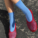 Red mesh shoes with blue socks on a dark surface