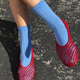 Red mesh shoes with blue socks on a dark surface