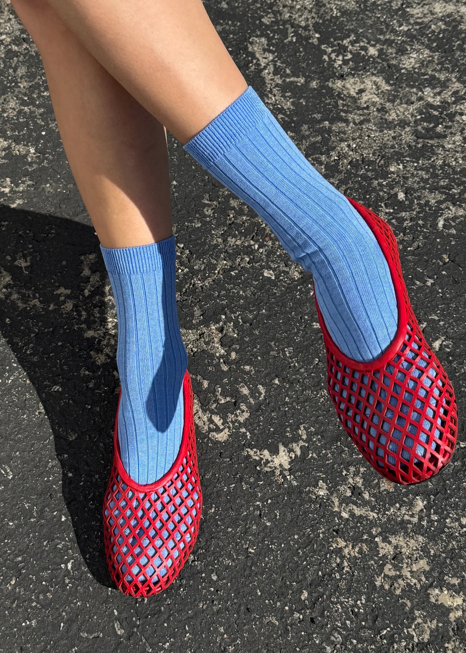 Red mesh shoes with blue socks on a dark surface