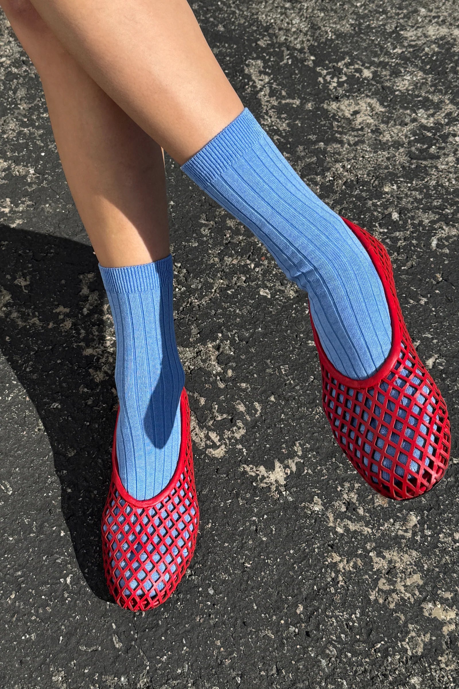 Red mesh shoes with blue socks on a dark surface