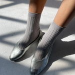 Person wearing silver shoes and gray socks on a concrete surface