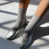 Person wearing silver shoes and gray socks on a concrete surface
