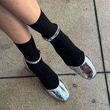 Person wearing black socks and silver shoes on a concrete surface
