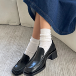Person wearing black shoes, white socks, and blue jeans on a neutral background