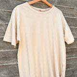 Beige t-shirt on a wooden hanger against a wooden background