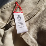 Close-up of a beige garment with a white tag featuring text and a logo.