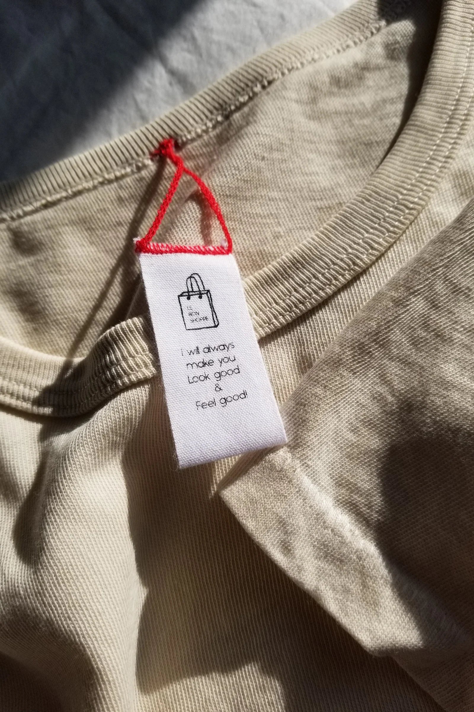 Close-up of a beige garment with a white tag featuring text and a logo.