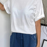 A person wearing a classic white dolman tee-shirt with relaxed fit, paired with blue jeans.