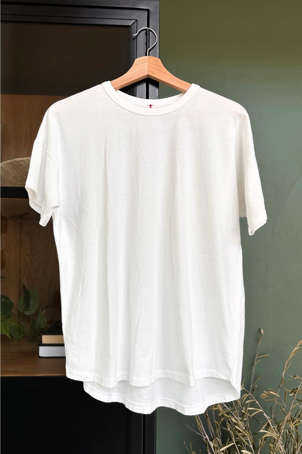 White tee shirt on a woo hanger on a cabinet