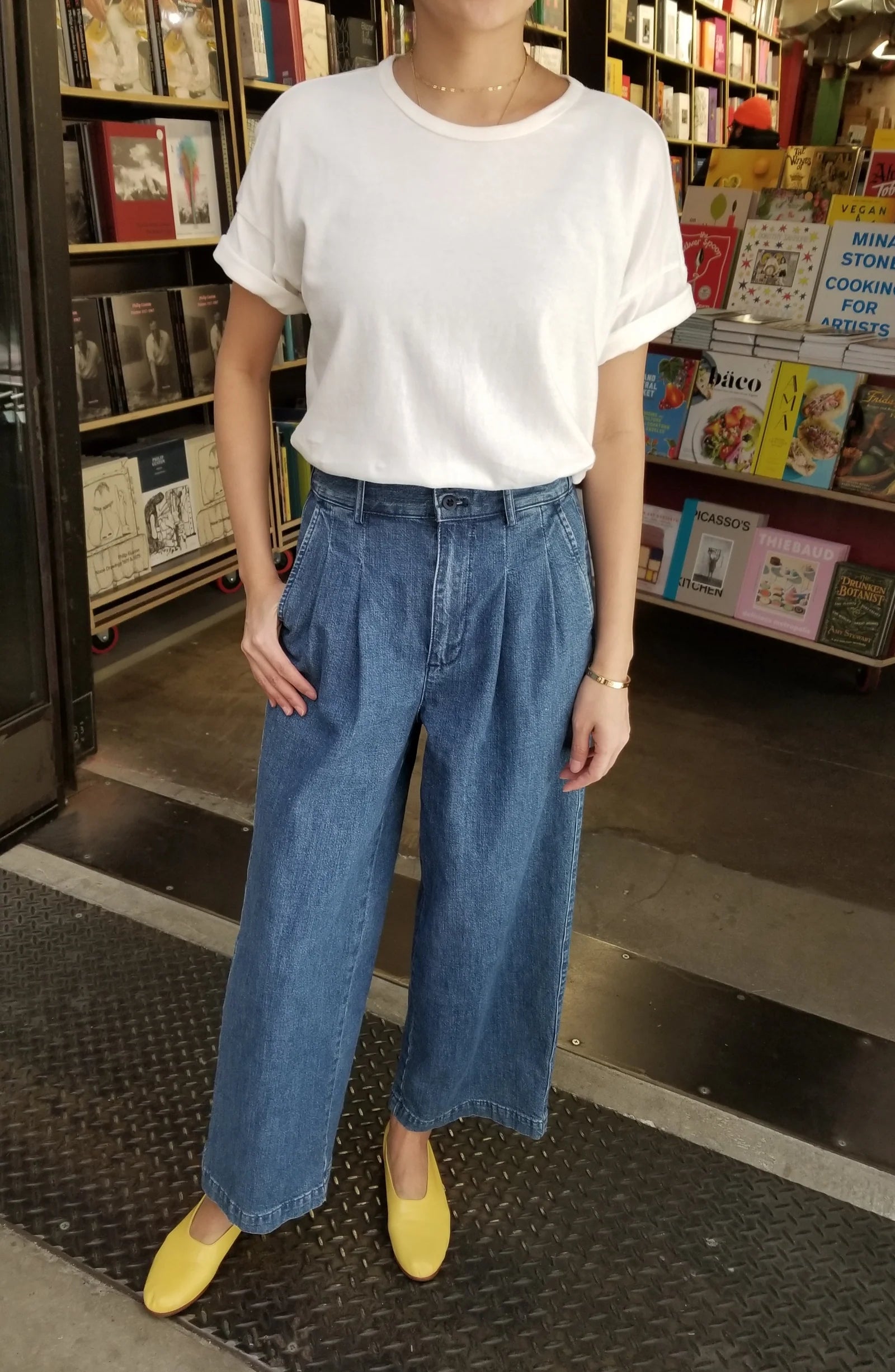 Person wearing white tee shirt, jeans and yellow shoes in a book store