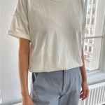 A person wearing a classic white dolman tee-shirt with relaxed fit, paired with blue jeans.