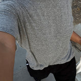 Person wearing a gray t-shirt and black pants on a concrete surface.