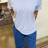 Person wearing a light blue t-shirt and blue pants in an indoor setting.