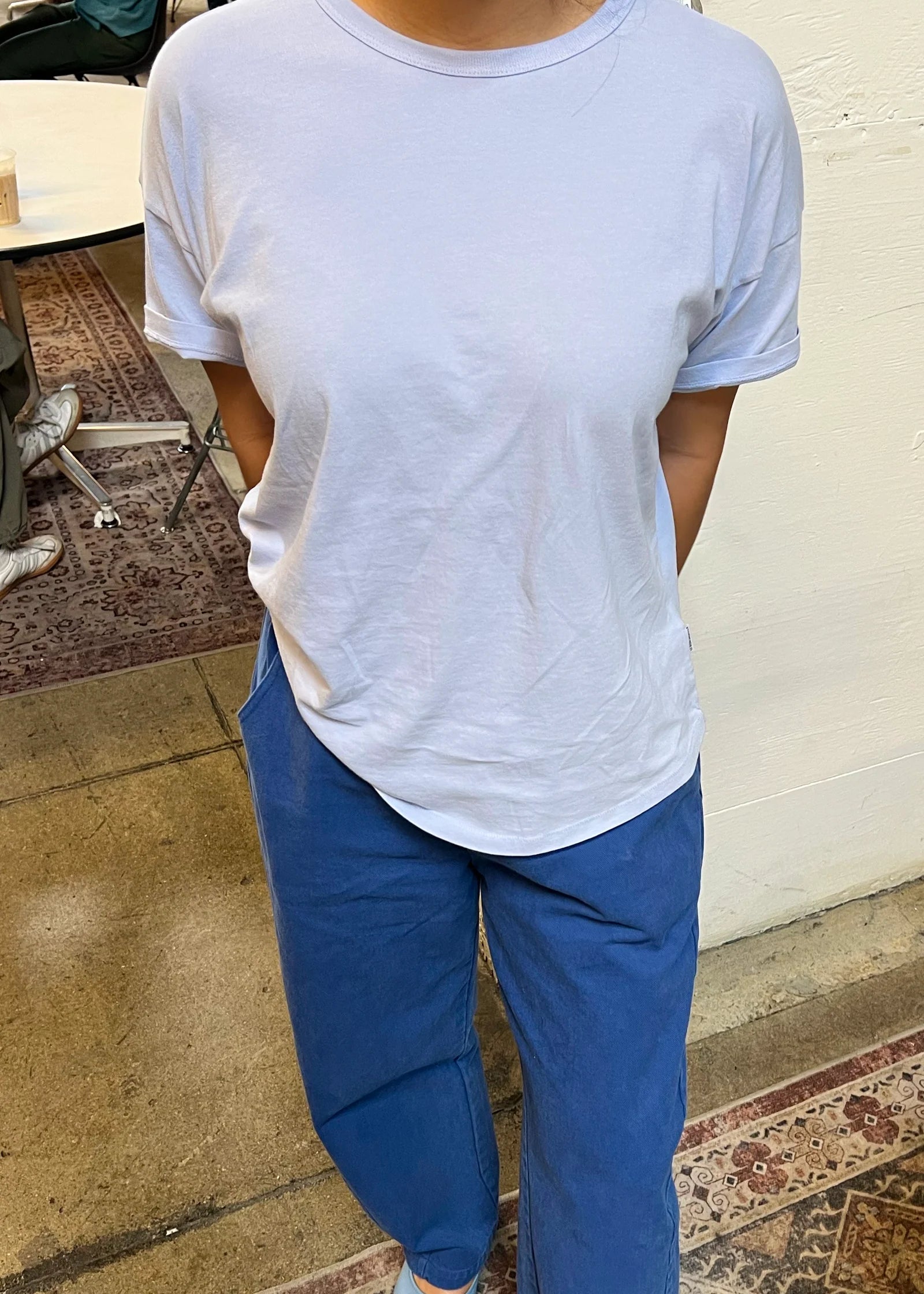 Person wearing a light blue t-shirt and blue pants in an indoor setting.