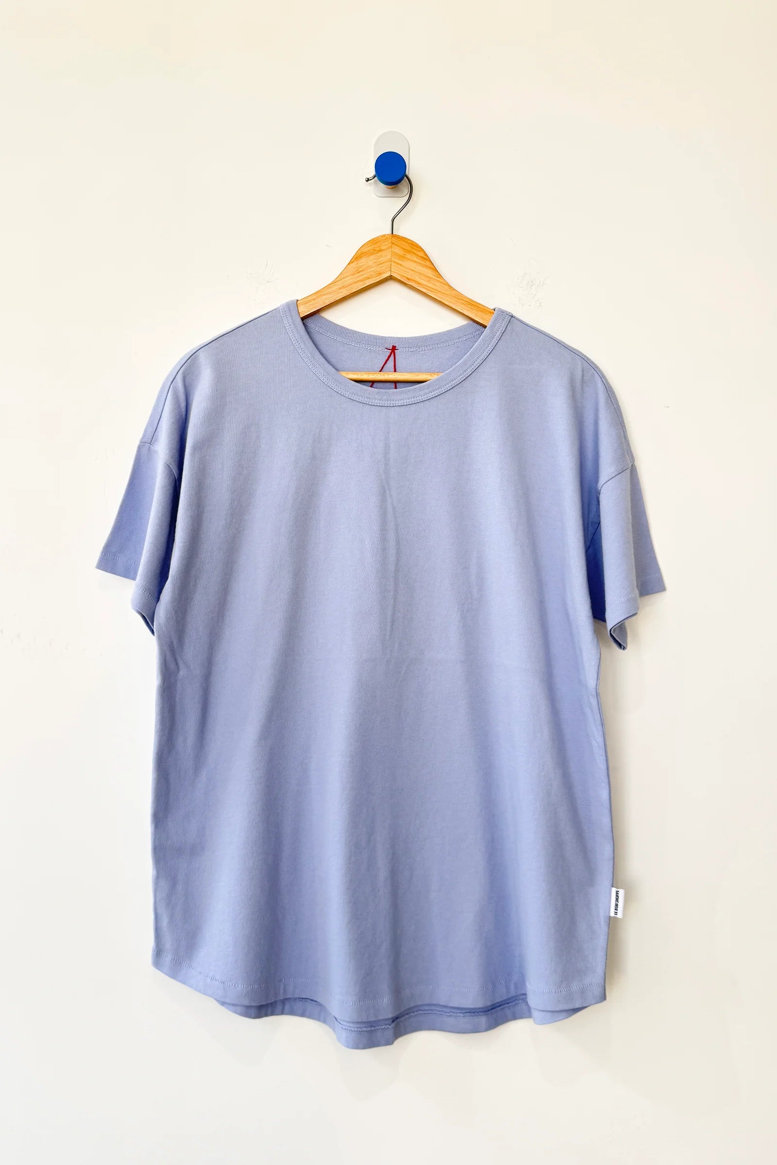 Light blue t-shirt on a wooden hanger against a white background