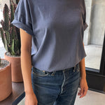 A person wearing a vintage navy colored dolman tee with short sleeves, paired with blue jeans.