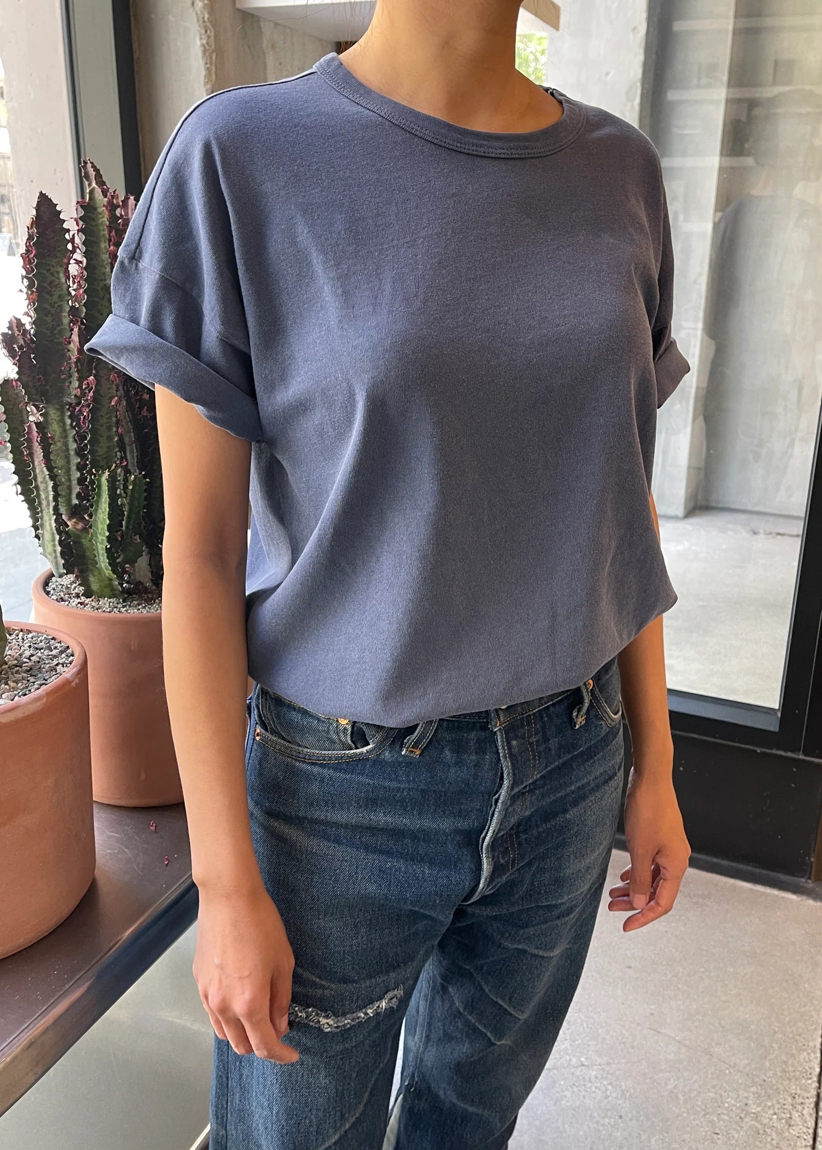 A person wearing a vintage navy colored dolman tee with short sleeves, paired with blue jeans.