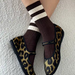 A pair of brown, white, and black striped socks worn with leopard print shoes.