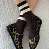 A pair of brown, white, and black striped socks worn with leopard print shoes.
