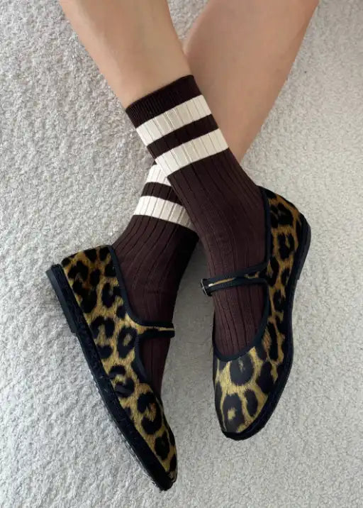 A pair of brown, white, and black striped socks worn with leopard print shoes.