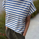 Person wearing a blue and white striped shirt with green pants outdoors.