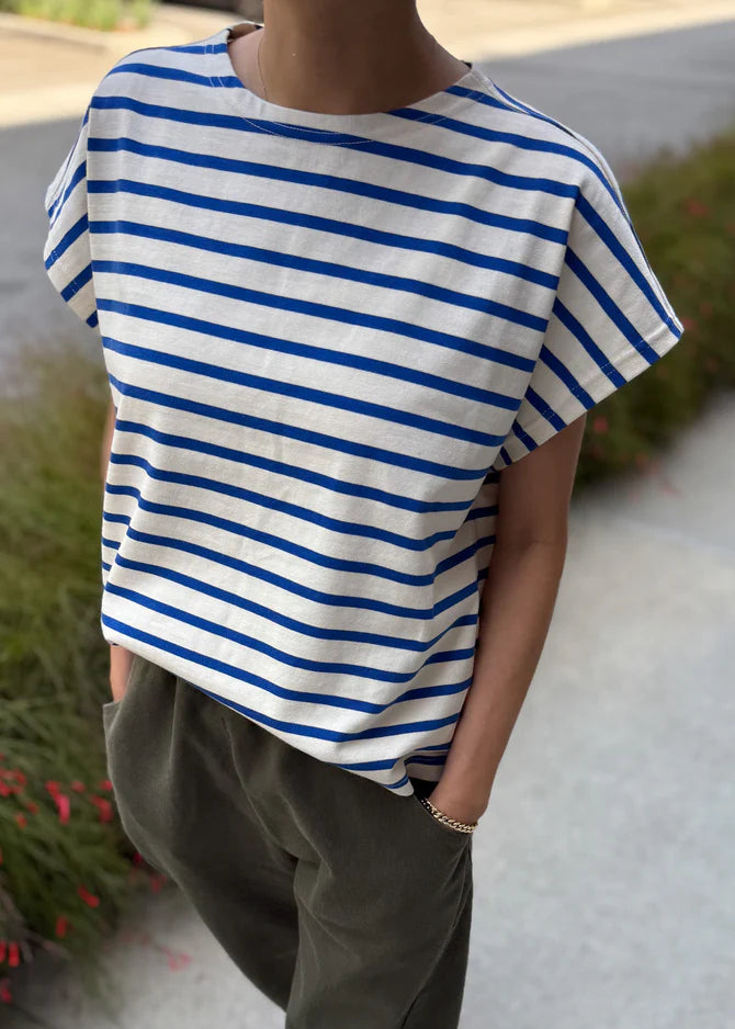 Person wearing a blue and white striped shirt with green pants outdoors.