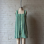 Green and white striped dress on a mannequin against a textured wall.