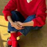 Person wearing a red sweater, blue jeans, red socks, and leopard print shoes on a yellow floor.