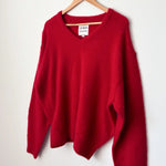 Red sweater on a wooden hanger against a white background