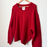 Red sweater on a wooden hanger against a white background