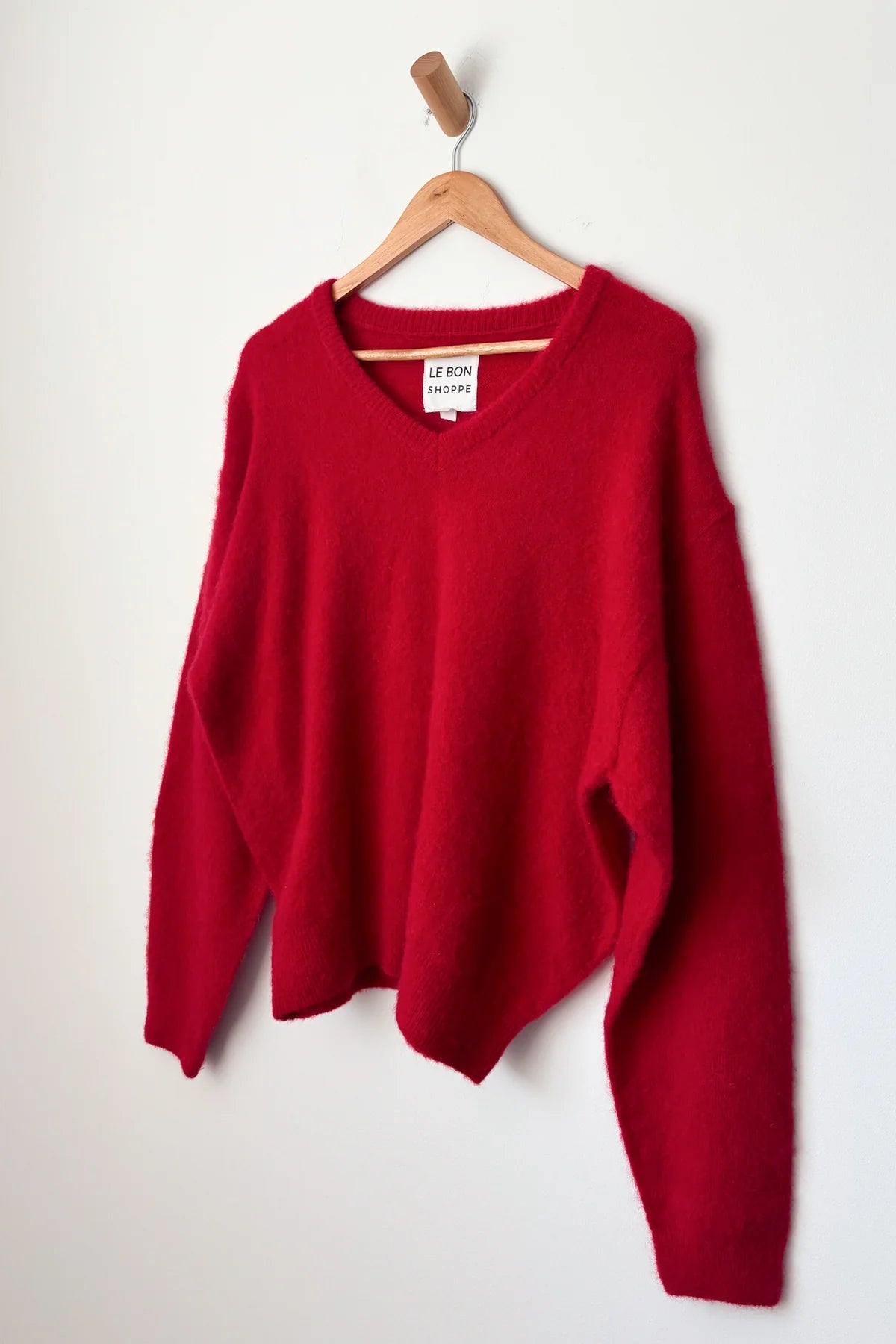 Red sweater on a wooden hanger against a white background