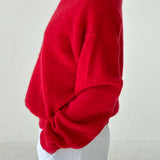 Red sweater worn by a person on a plain background