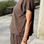 Person wearing a brown outfit standing on a sidewalk.