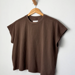 Brown t-shirt on a wooden hanger against a white background
