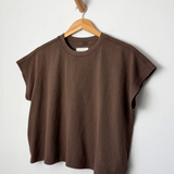 Brown t-shirt on a wooden hanger against a white background