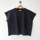 Black sleeveless top on a wooden hanger against a white background
