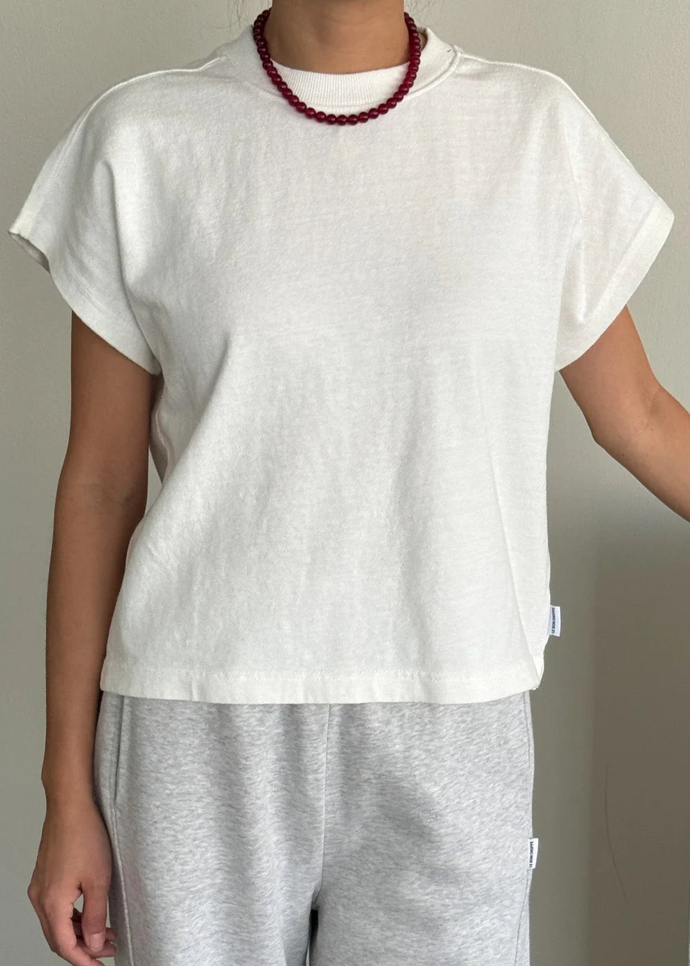 Person wearing a white t-shirt and gray pants against a neutral background