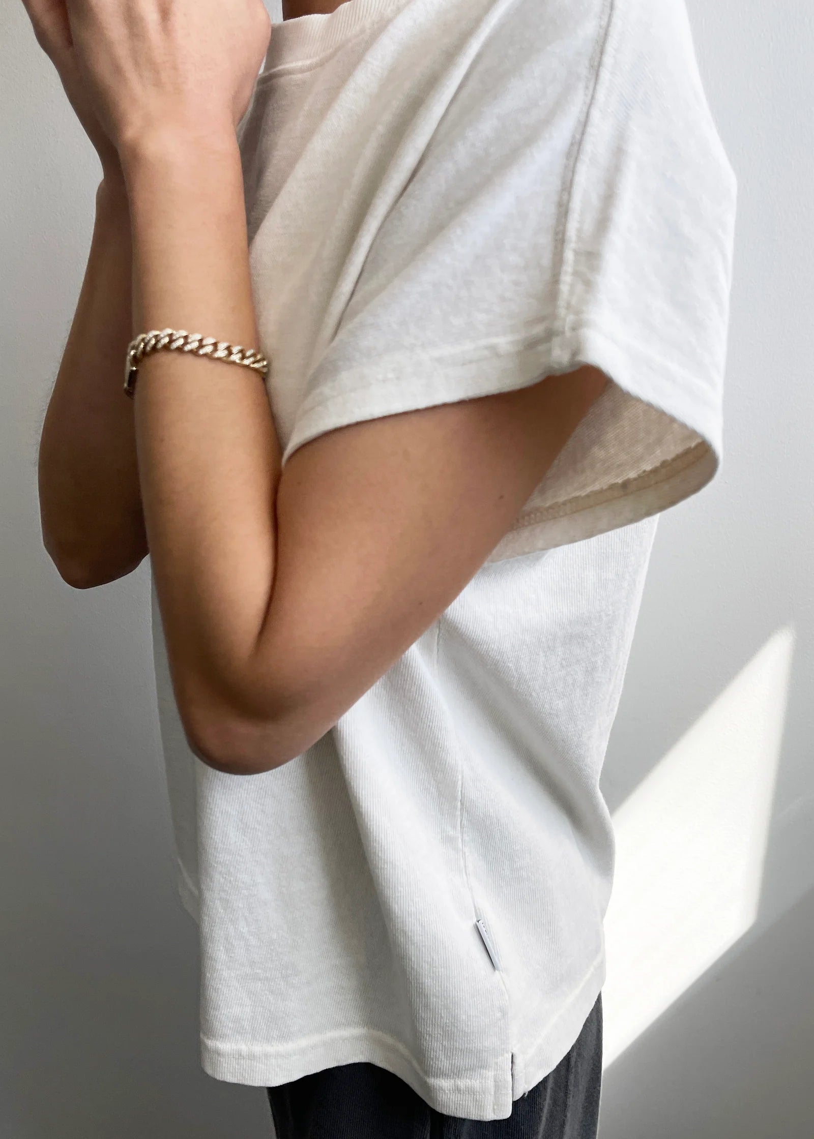 Person wearing a white oversized t-shirt with a neutral background