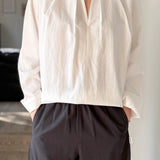 Person wearing a white blouse and dark pants in an indoor setting