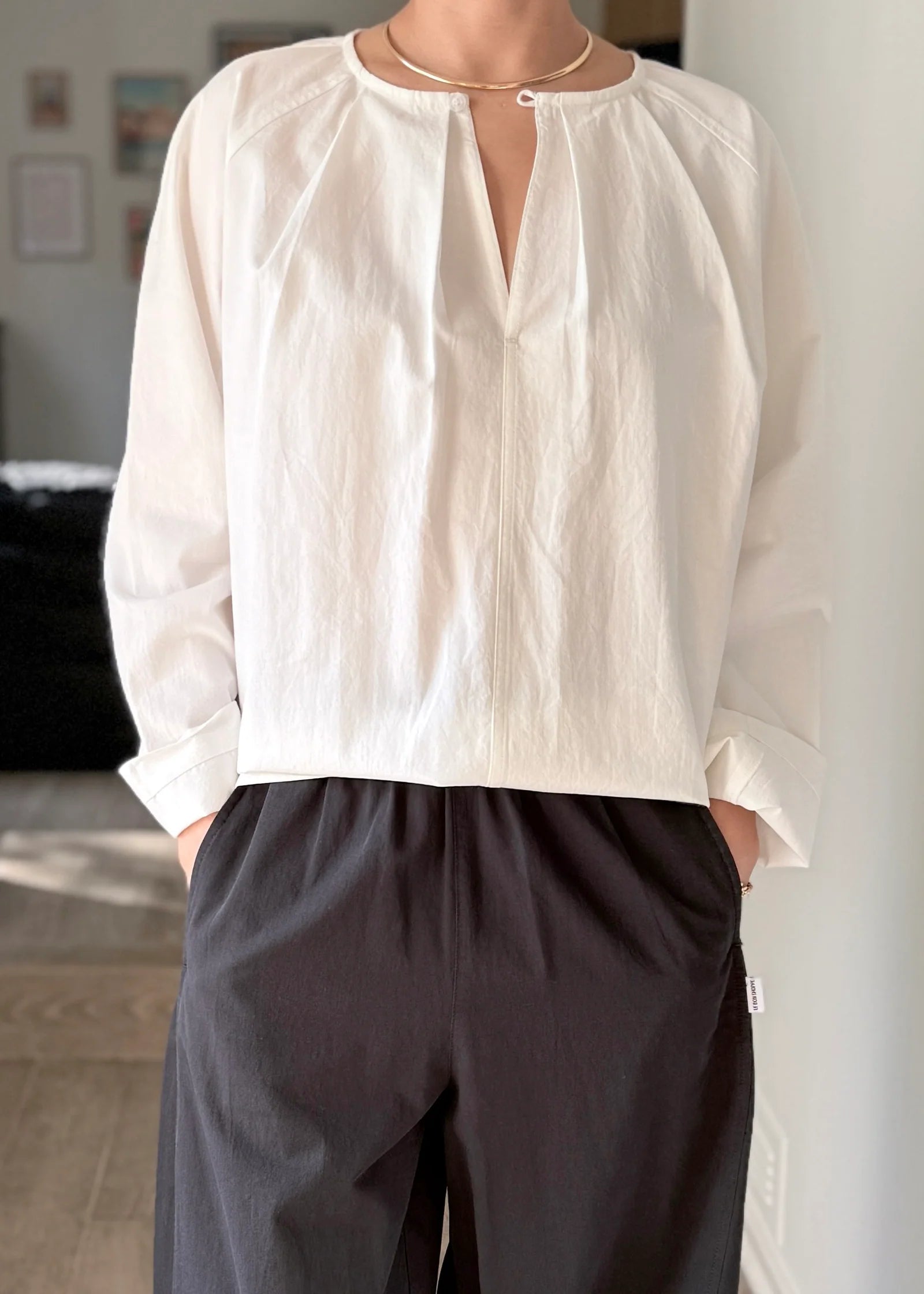 Person wearing a white blouse and dark pants in an indoor setting