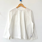 White blouse on a wooden hanger against a white background