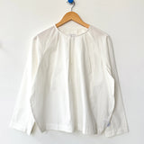 White blouse on a wooden hanger against a white background