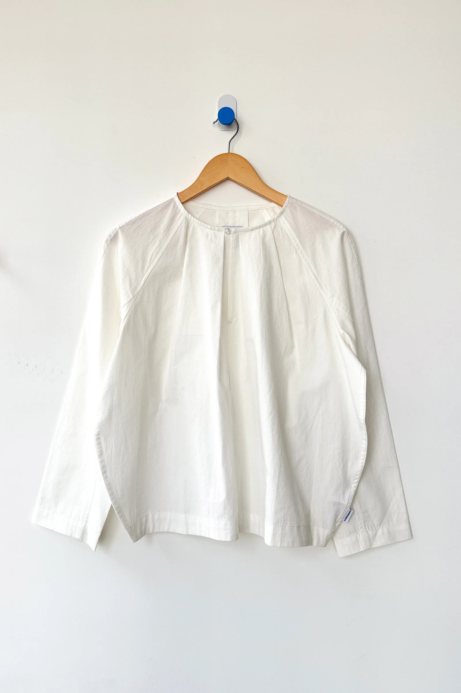 White blouse on a wooden hanger against a white background