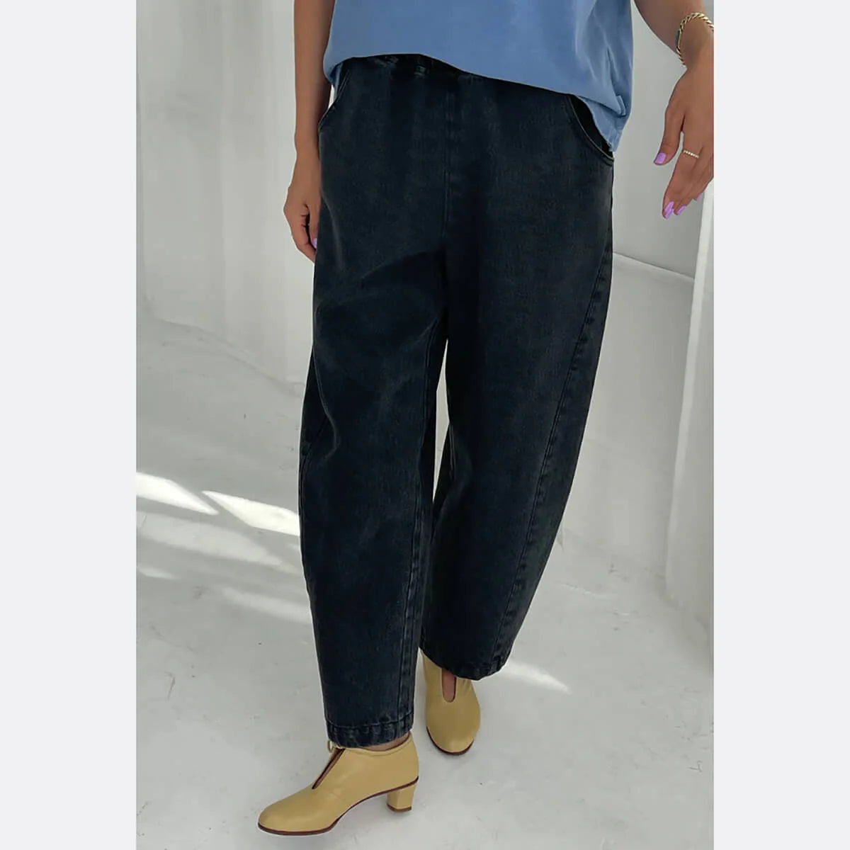 Person wearing black jeans and a blue top on a white background