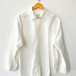 White shirt on a wooden hanger against a white background