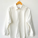 White shirt on a wooden hanger against a white background