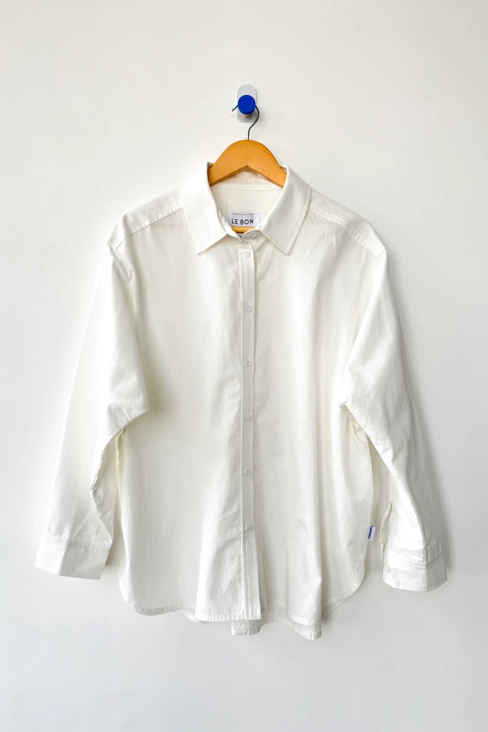White shirt on a wooden hanger against a white background