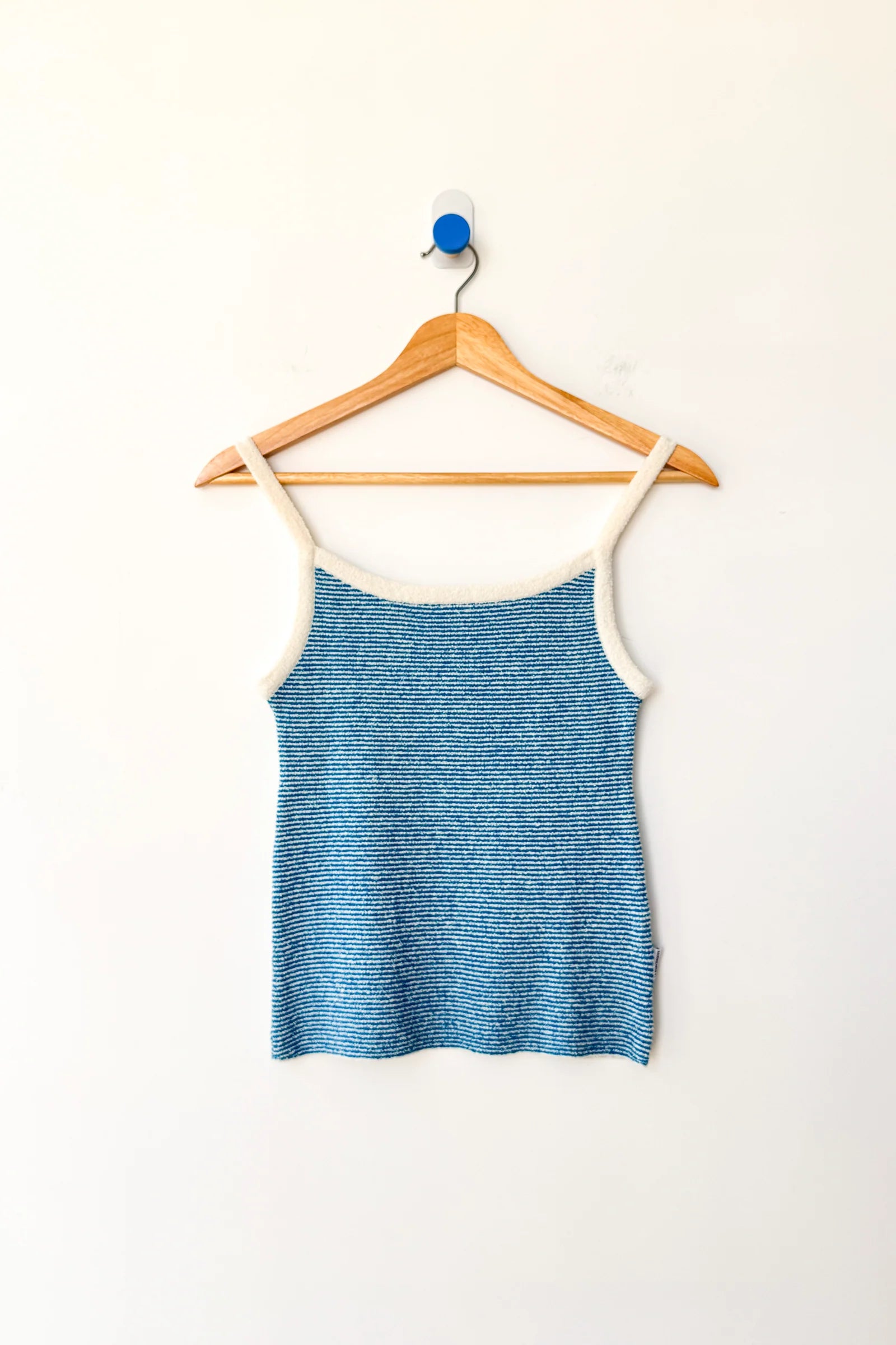 Blue tank top on a wooden hanger against a white background